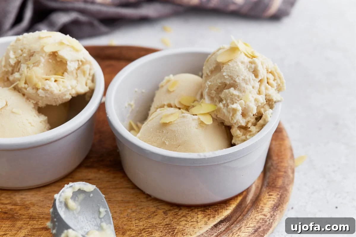 Creamy Almond Dream 10 Side view of two bowls filled with almond milk ice cream, each topped with sliced almonds on a wood surface.
