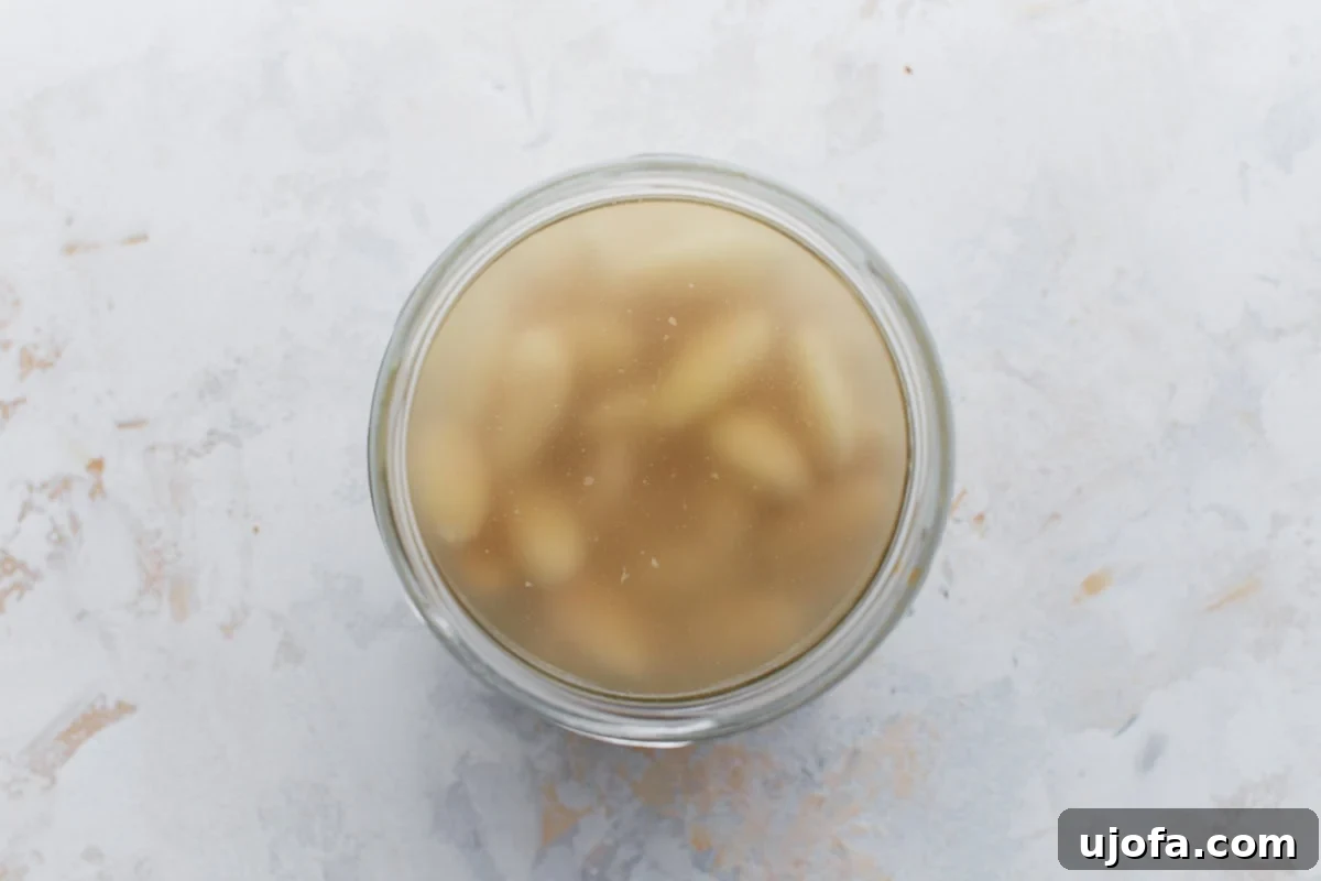 Creamy Almond Dream 5 Top-down view of a glass jar filled with soaked blanched almonds in water.
