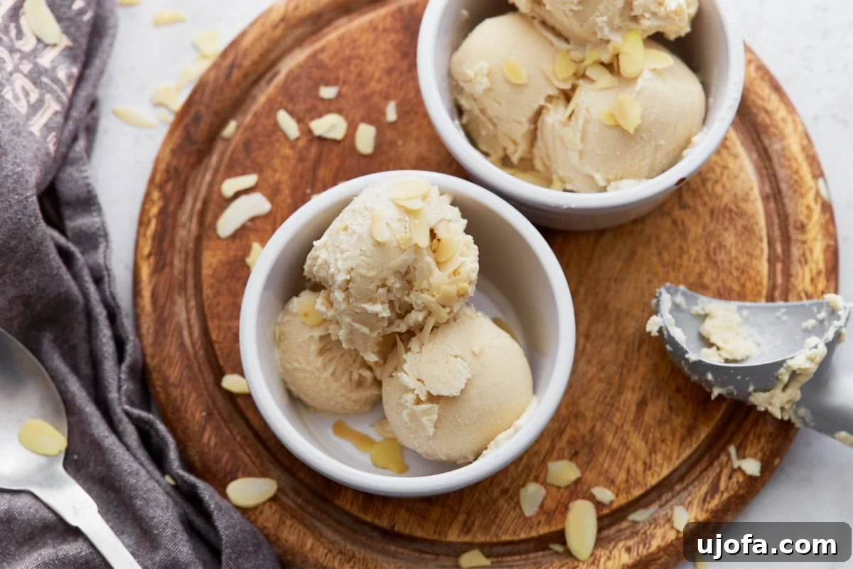 Creamy Almond Dream 9 Two ramekins filled with scoops of almond milk ice cream on a wooden board, garnished with sliced almonds and a scoop resting on the side.
