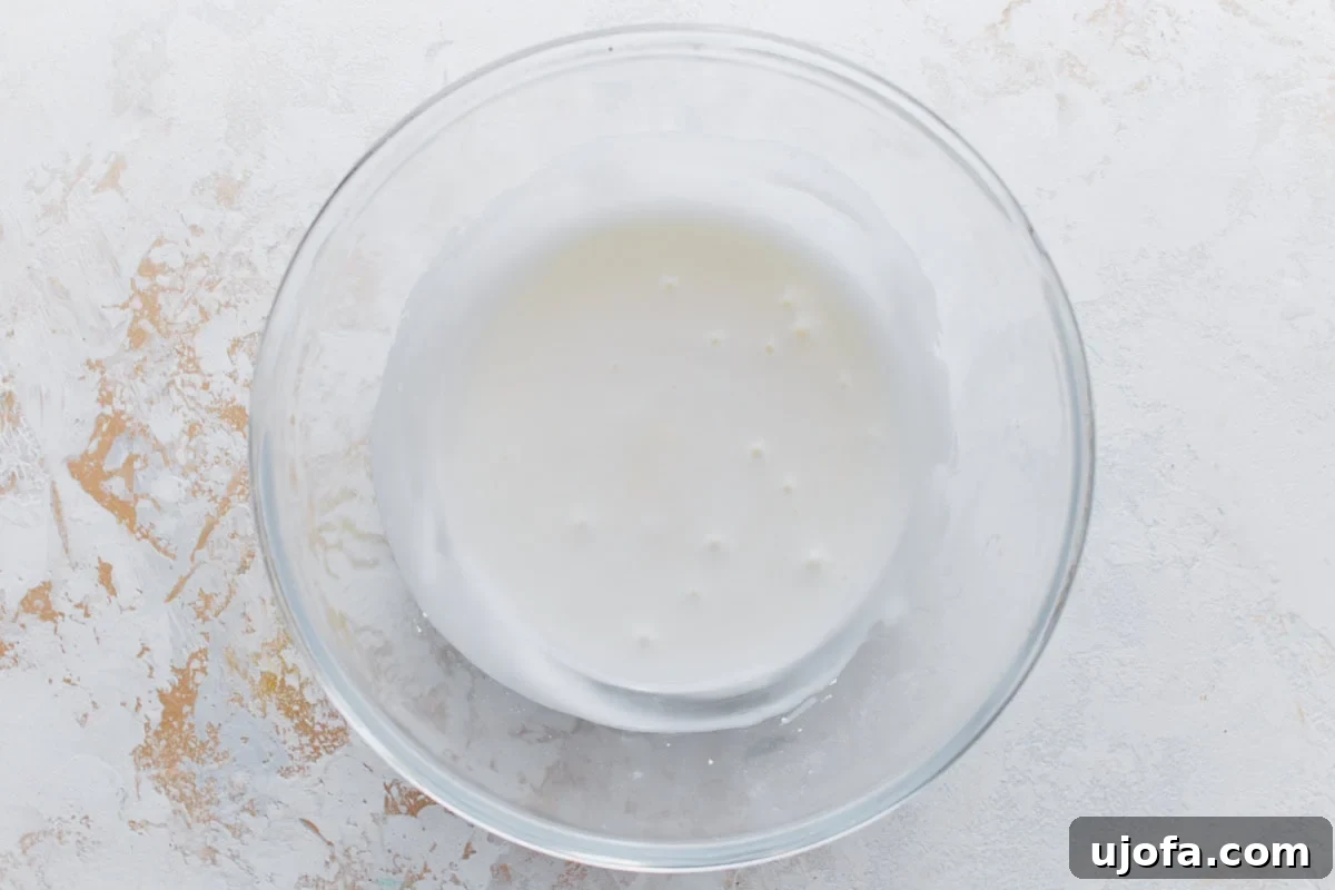 Lemon glaze mixture in a clear bowl, smooth and white.