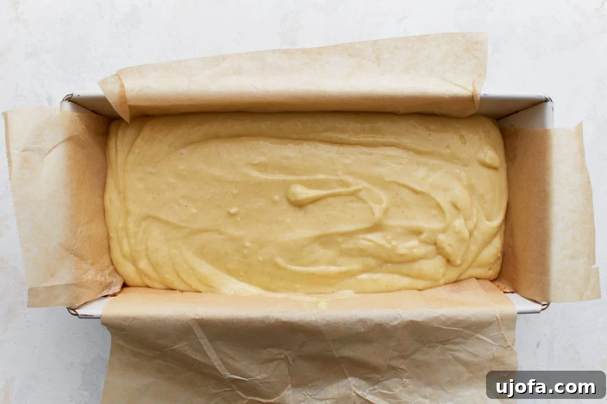Lemon loaf batter poured into a parchment-lined loaf pan, ready for baking.