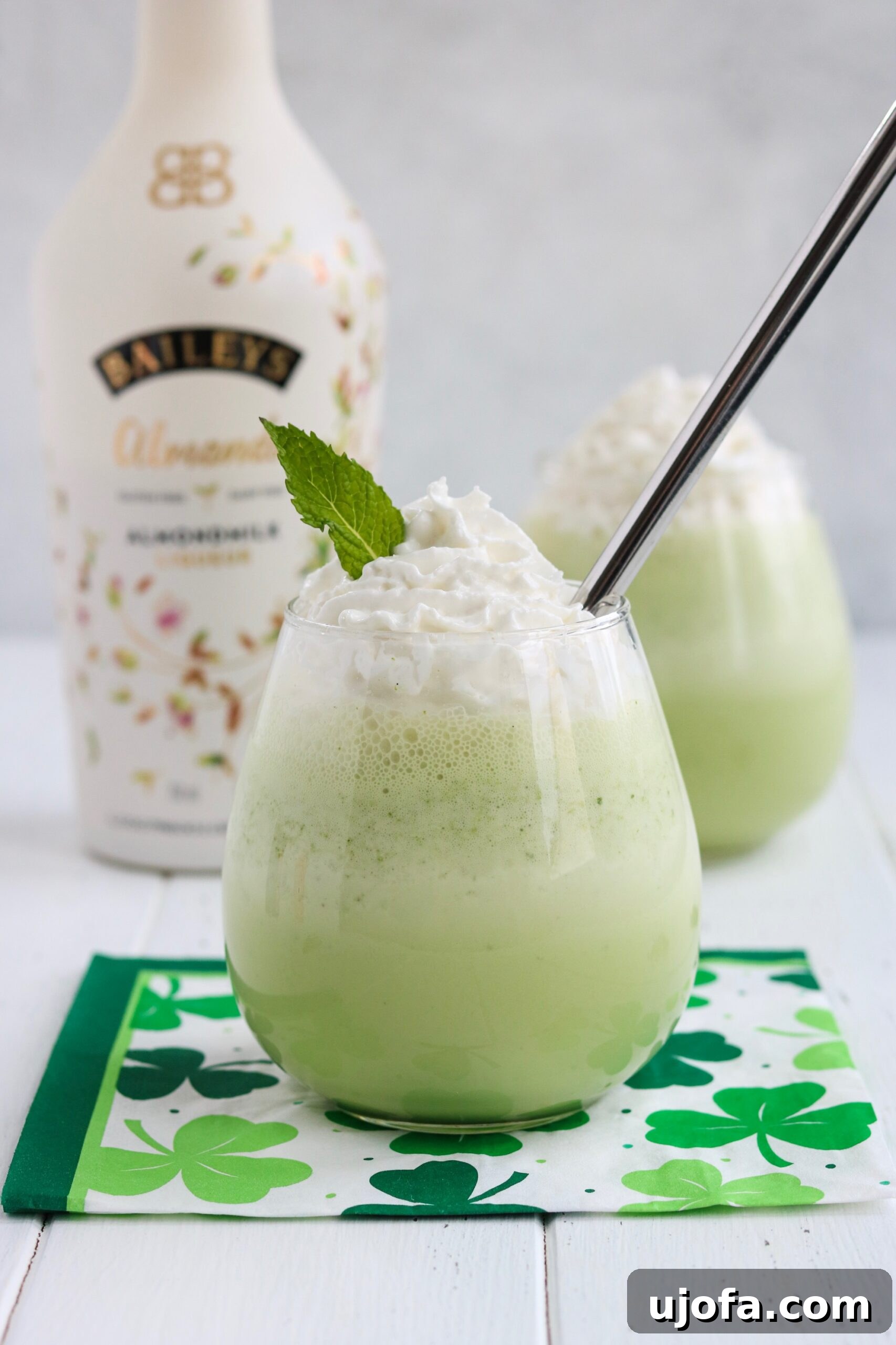 A vibrant green Spiked Shamrock Shake in a tall glass, garnished with dairy-free whipped cream and a hint of mint. The shake is dairy-free, gluten-free, and vegan, making it an inclusive treat for St. Patrick's Day.