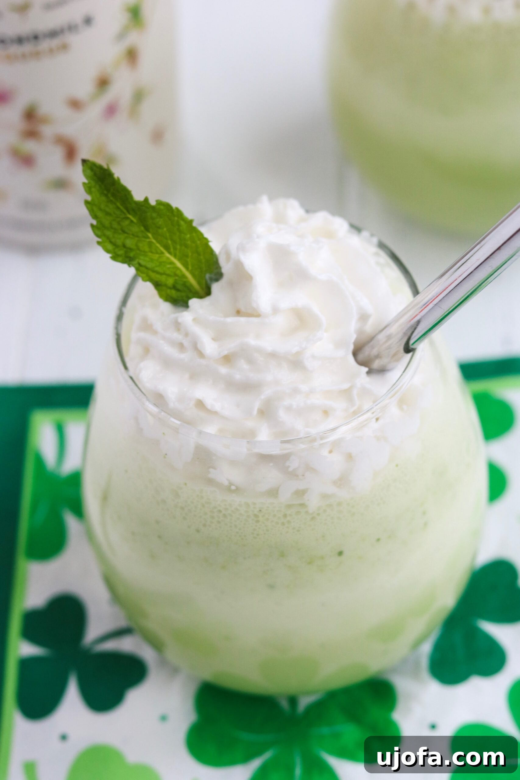 A beautifully presented Spiked Shamrock Shake, garnished with a generous swirl of dairy-free whipped cream, capturing the essence of a festive St. Patrick's Day beverage that's also healthy and delicious.