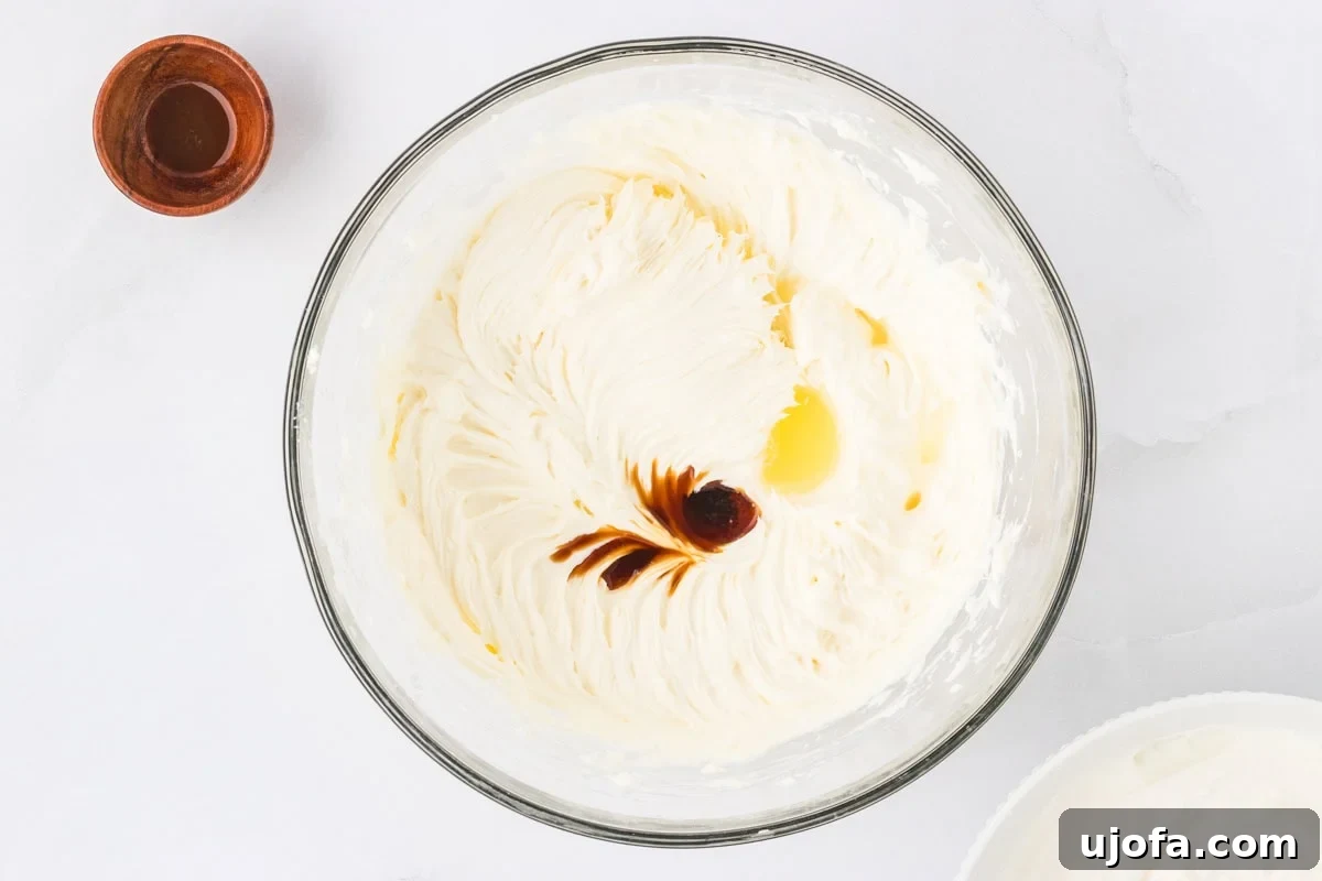 No-Oven Gluten-Free Cheesecake Bliss 10 The smoothly blended cream cheese filling in a mixing bowl, with a small pool of freshly added lemon juice and vanilla extract visible in the center, waiting to be gently mixed in for enhanced flavor.