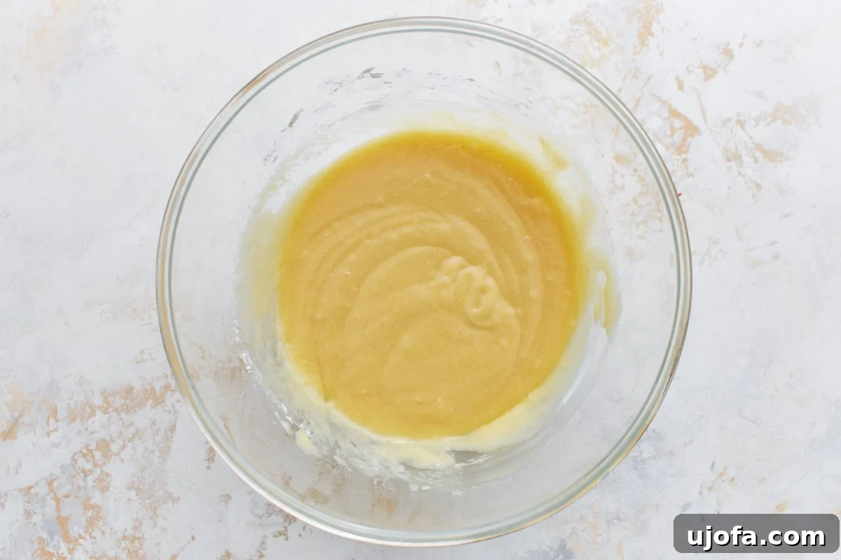 Easy Crustless Apple Pie 5 Smooth, mixed batter in a clear glass bowl, ready to be spread over the apple filling.
