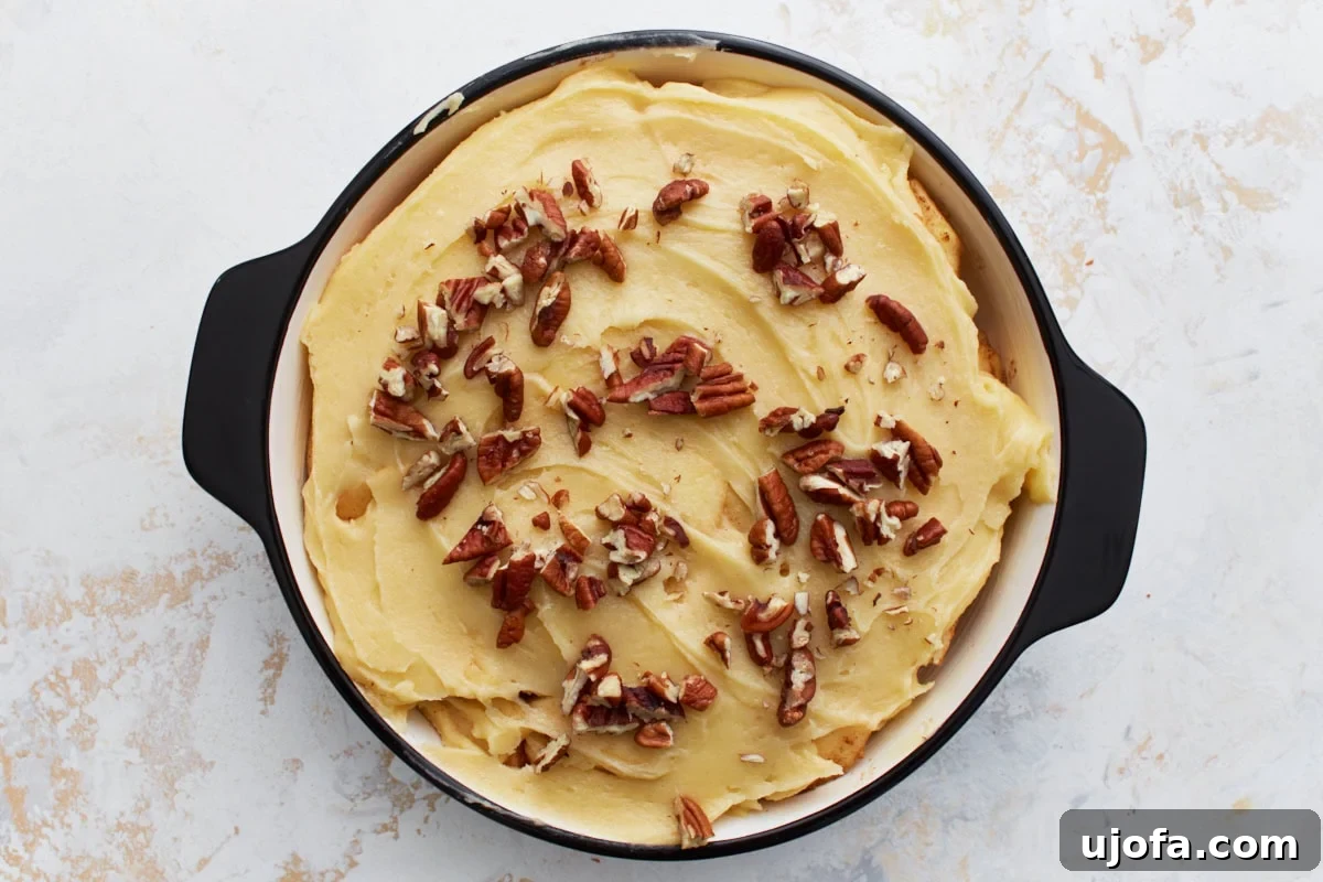 Easy Crustless Apple Pie 7 Batter spread over the apple layer in the baking dish and topped with chopped pecans before baking.