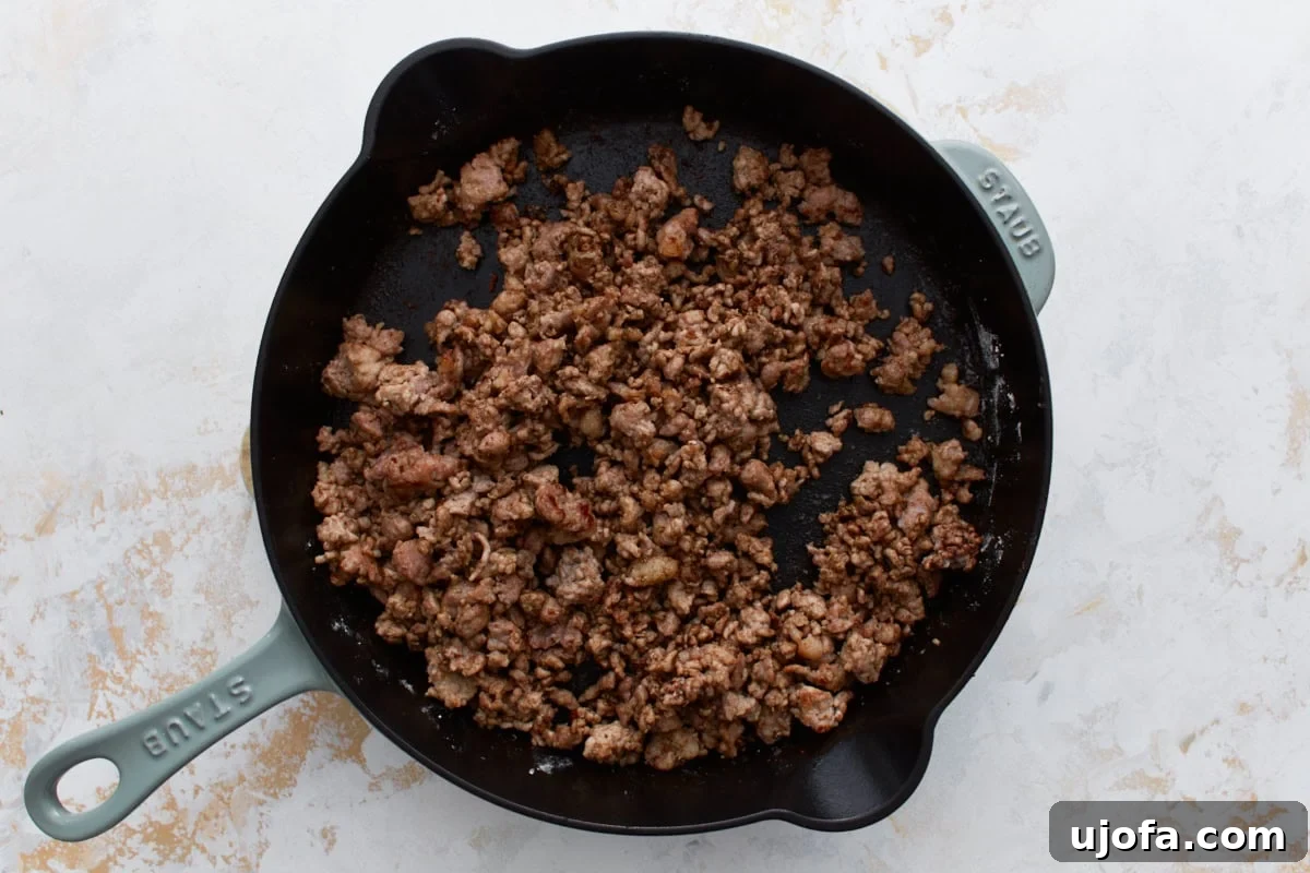 Creamy Gluten-Free Sausage Gravy 6 Crumbled sausage in a cast iron skillet, evenly coated with gluten-free flour and spices, forming a fragrant roux for the rich gravy.