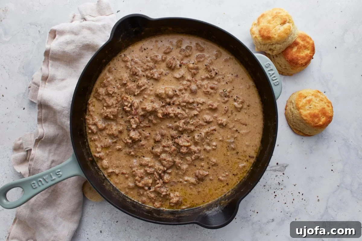 Creamy Gluten-Free Sausage Gravy 8 A close-up of fully cooked gluten-free sausage gravy in a cast iron skillet, showcasing its creamy, rich texture and inviting warmth, ready to be served.