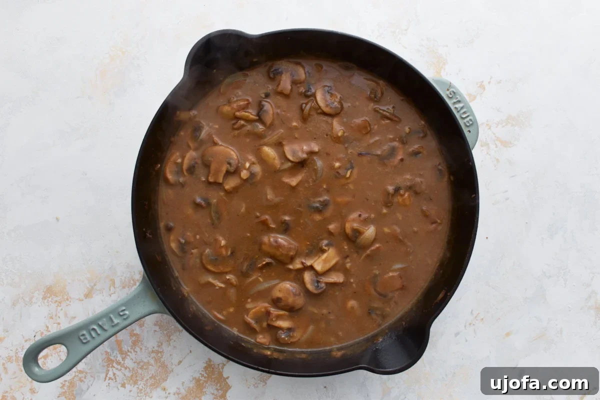 The sauce starting to thicken as it simmers with mushrooms and onions.
