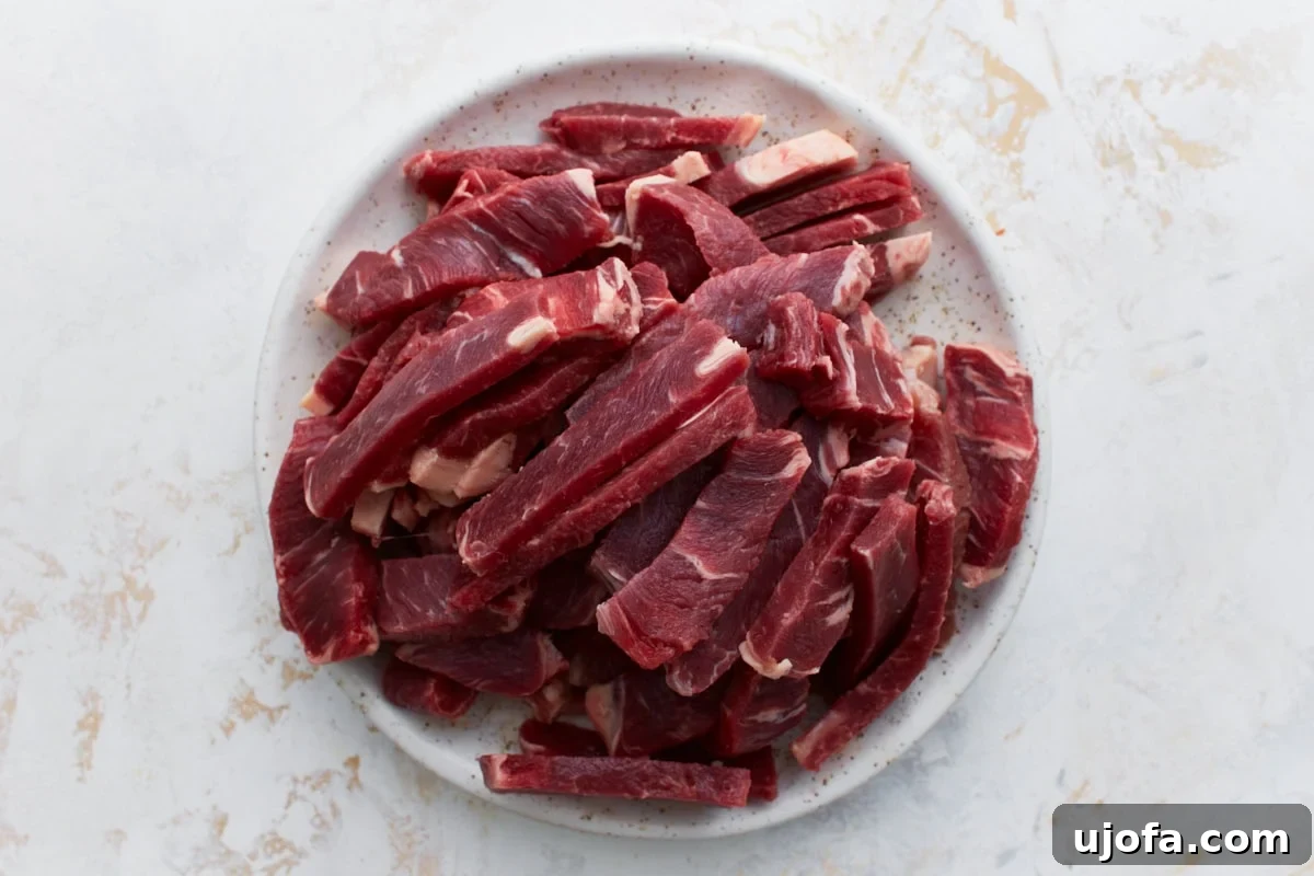 Plate of thinly sliced raw beef sirloin, ready for searing.