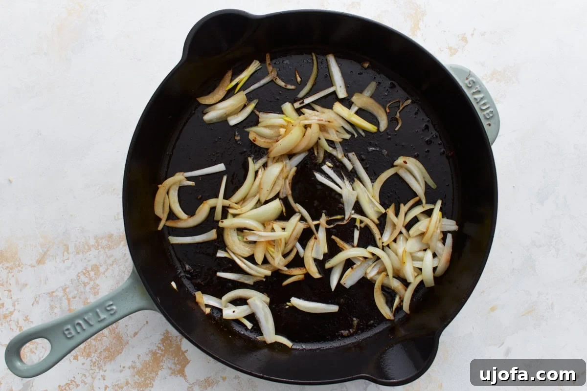 Sliced onions sautéing in the same skillet after the beef has been removed.