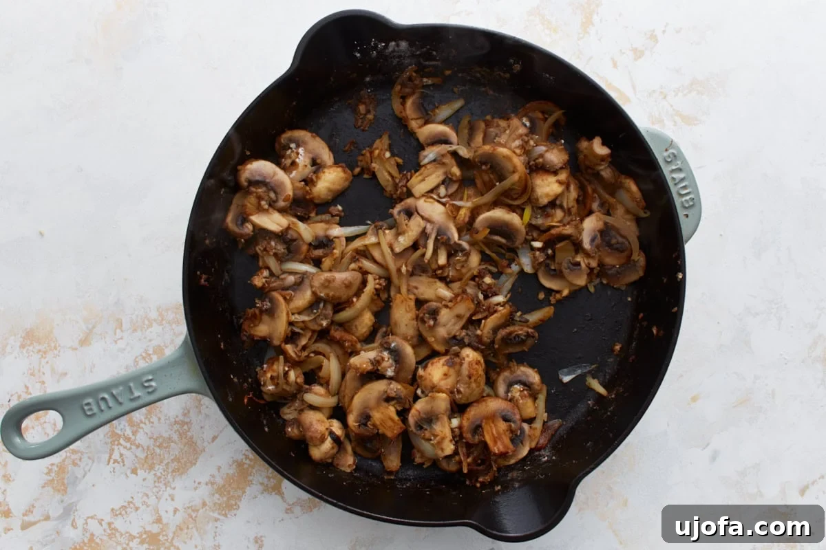 Mushroom and onion mixture in the skillet with flour sprinkled over, ready to be stirred and thickened.