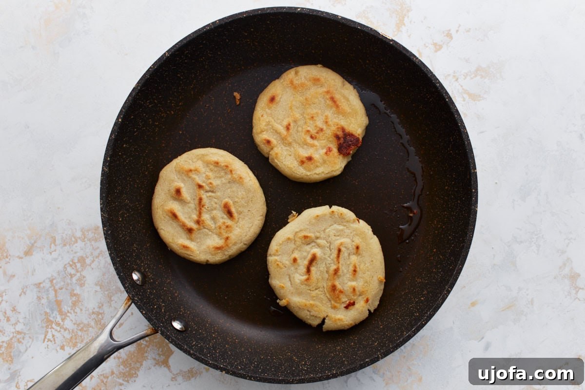 Savory Salvadoran Pockets 11 Three pupusas cooking in a skillet, lightly browned and developing charred spots.