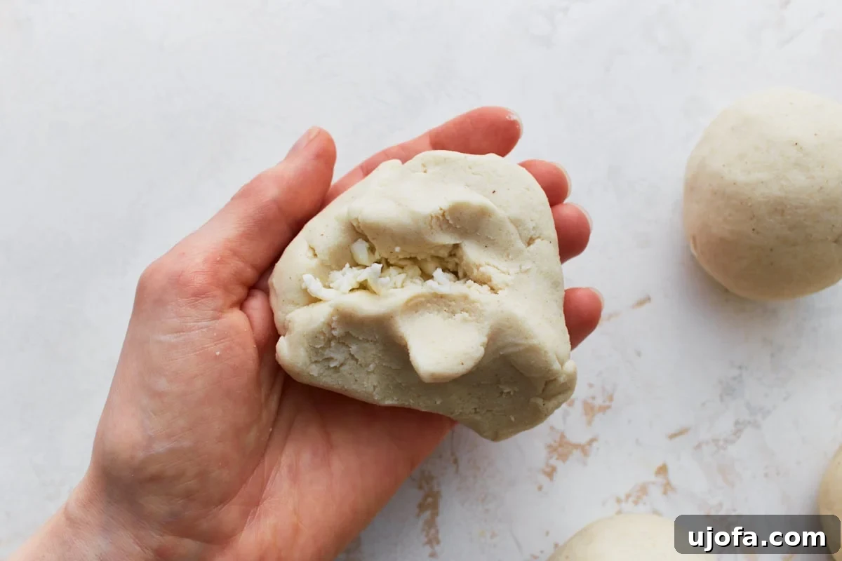 Savory Salvadoran Pockets 9 Masa dough being folded over cheese filling in a hand, showing the pupusa being sealed.