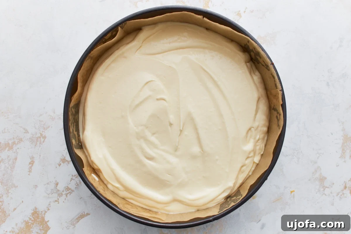 Decadent Keto Cheesecake 11 Unbaked cheesecake filling spread evenly over the crust in a springform pan.