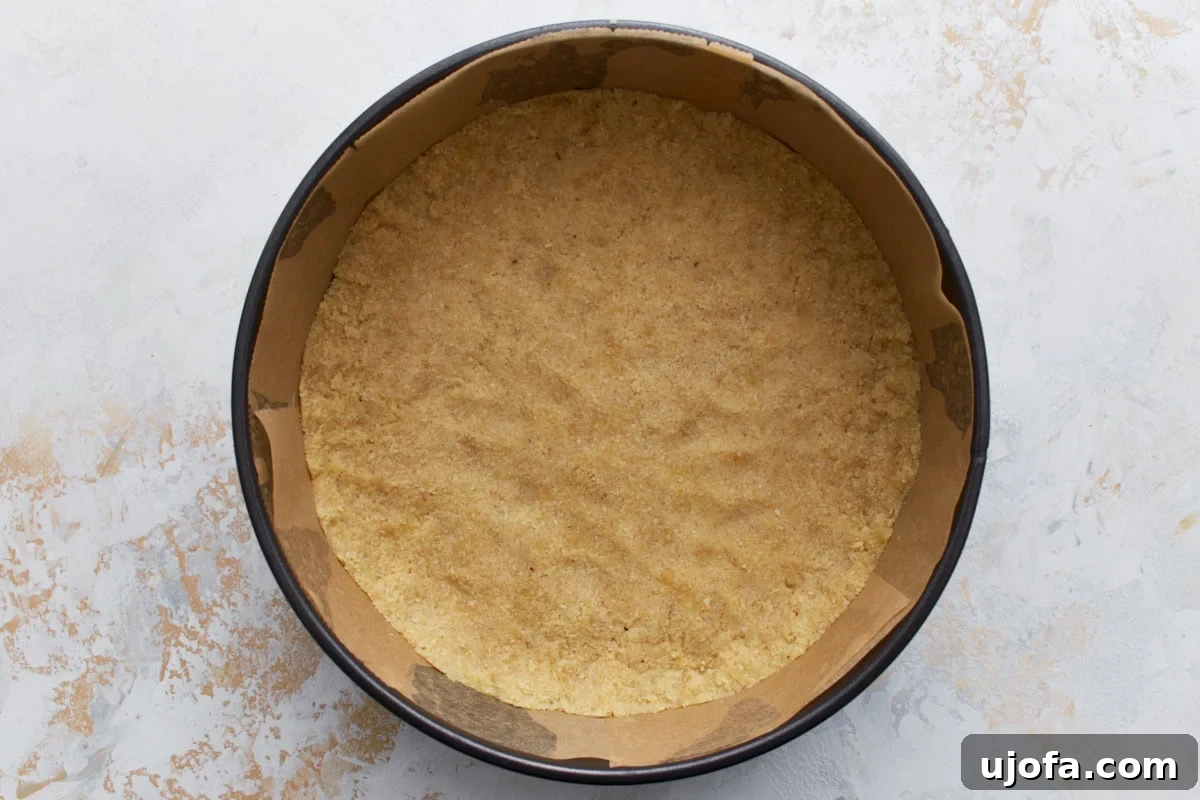 Decadent Keto Cheesecake 6 Unbaked almond flour crust pressed evenly into the bottom of a parchment-lined springform pan.