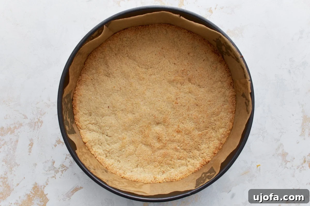 Decadent Keto Cheesecake 7 Golden-brown almond flour crust after baking, shown inside a parchment-lined springform pan.