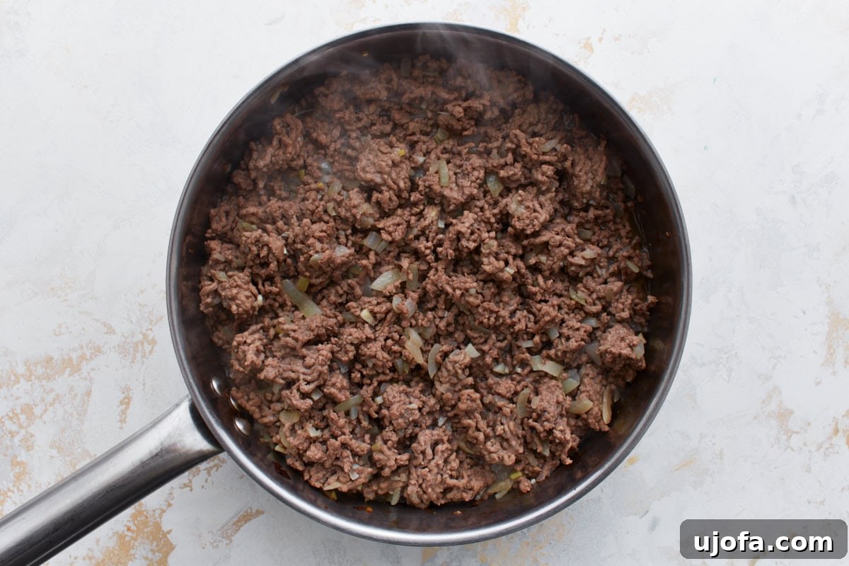 Hearty Keto Chili 6 Ground beef cooking with softened onions and garlic in a skillet, starting to brown and break apart.