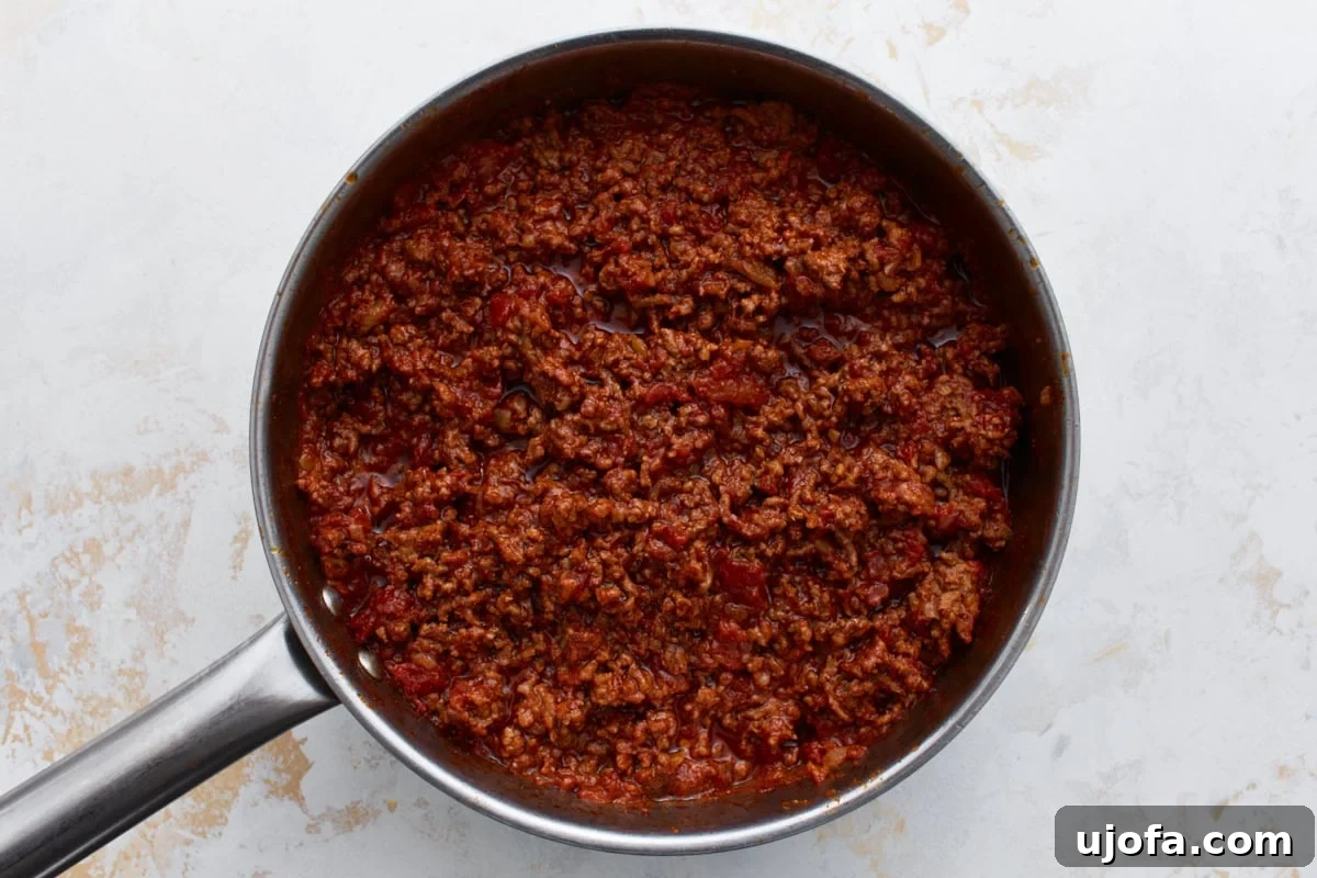 Hearty Keto Chili 8 Keto chili after a long simmer, thickened with a rich, meaty texture and deep color in a large skillet.