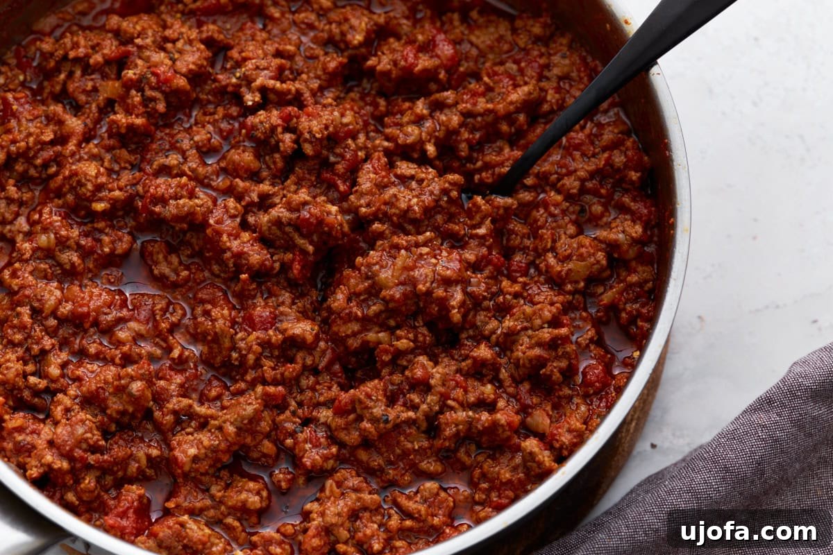 Hearty Keto Chili 9 A close-up view of thick, hearty keto chili in a skillet, with visible chunks of meat and tomato in a rich sauce.