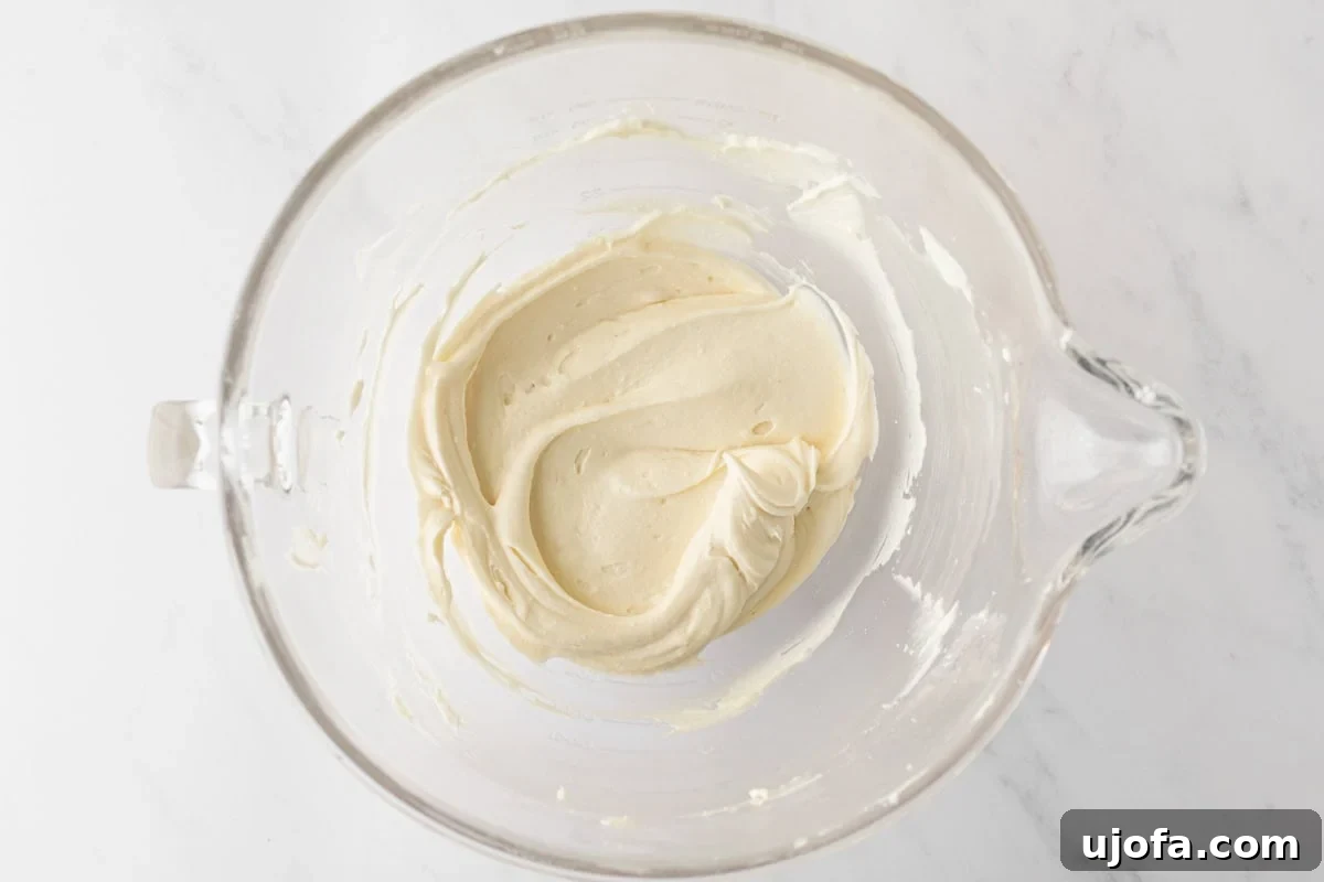 Smooth and fluffy cream cheese frosting in a clear mixing bowl, ready to spread on the cake.