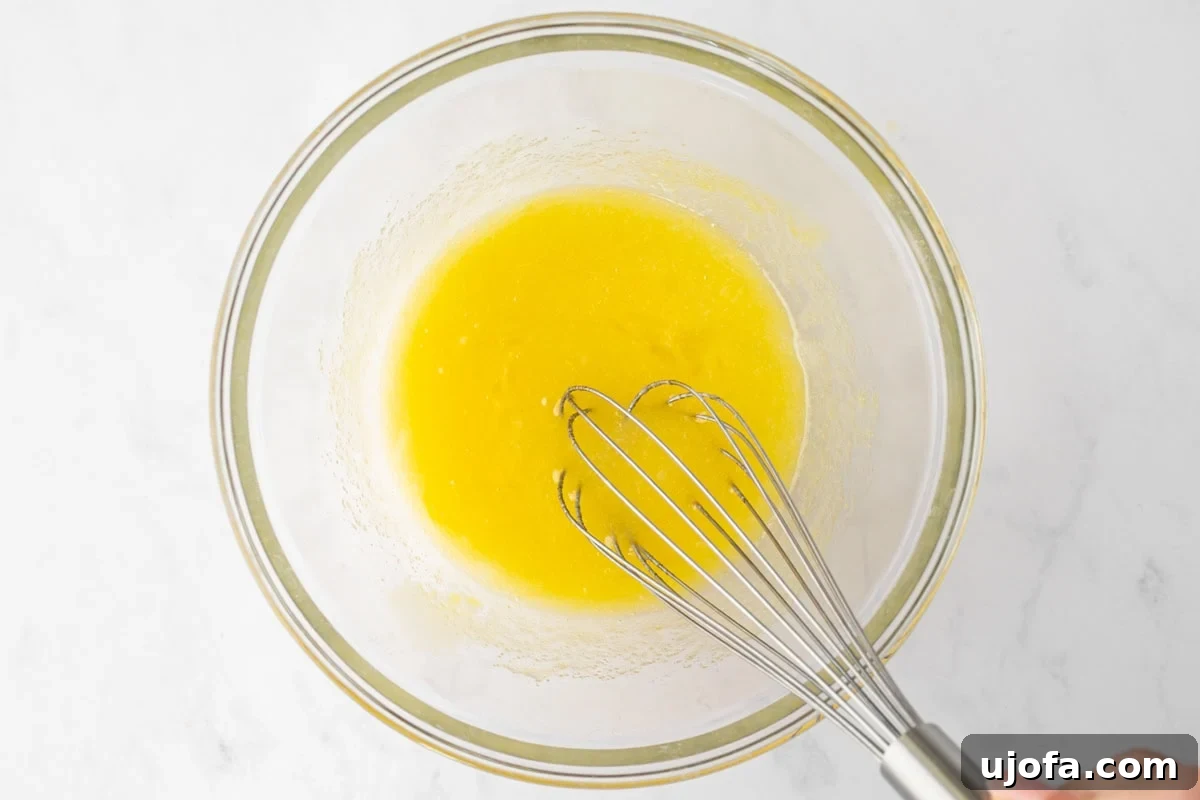 Glass bowl with whisked yellow mixture of sugar and oil for the gluten-free spice cake batter.