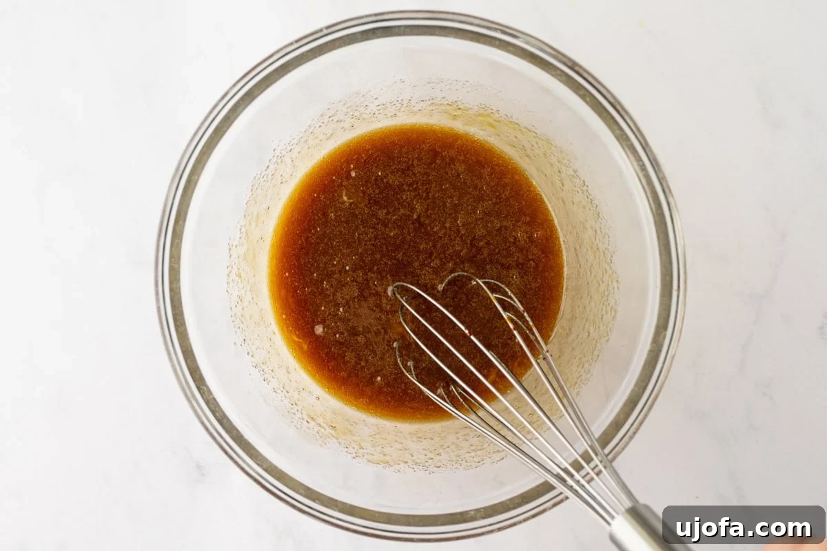 Glass bowl showing the wet ingredients mixed with molasses and vanilla, creating a deep brown color.