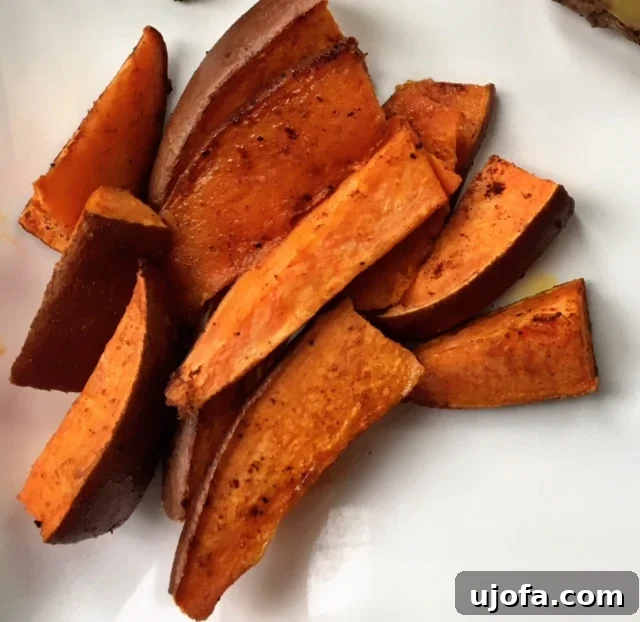 Crispy chili pumpkin spice sweet potato wedges on a baking sheet, golden brown and perfectly seasoned, ready to be served for a delightful fall meal.