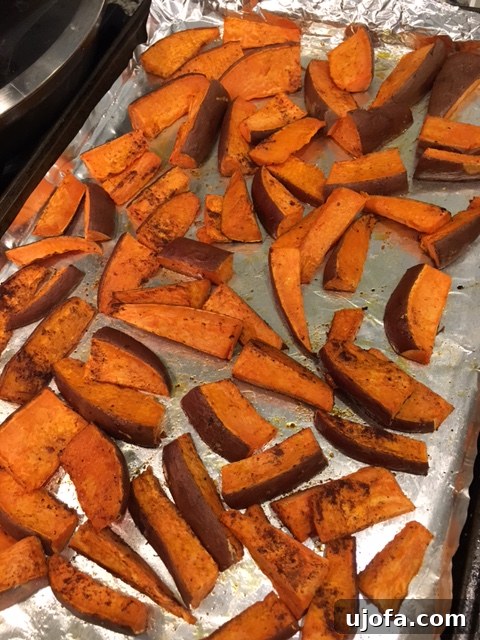 Close-up view of golden brown sweet potato wedges, showing off their perfect seasoning and crispy texture, piled artfully for a mouth-watering presentation.