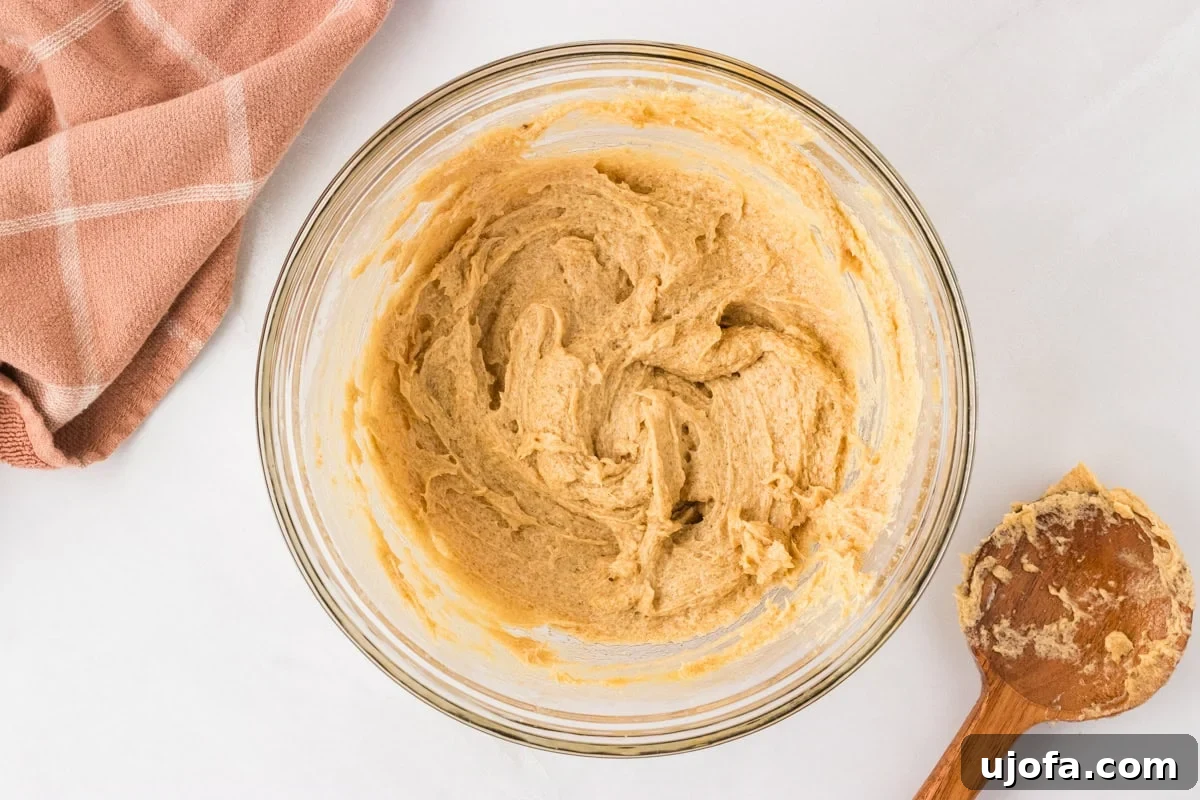 Smoothly mixed wet ingredients in a glass bowl, including egg and vanilla, ready for the dry ingredients to be added.
