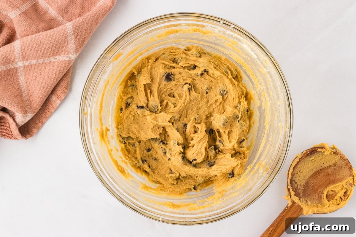 Cookie dough mixed with rich chocolate chips in a glass bowl, ready for scooping onto the baking sheet.
