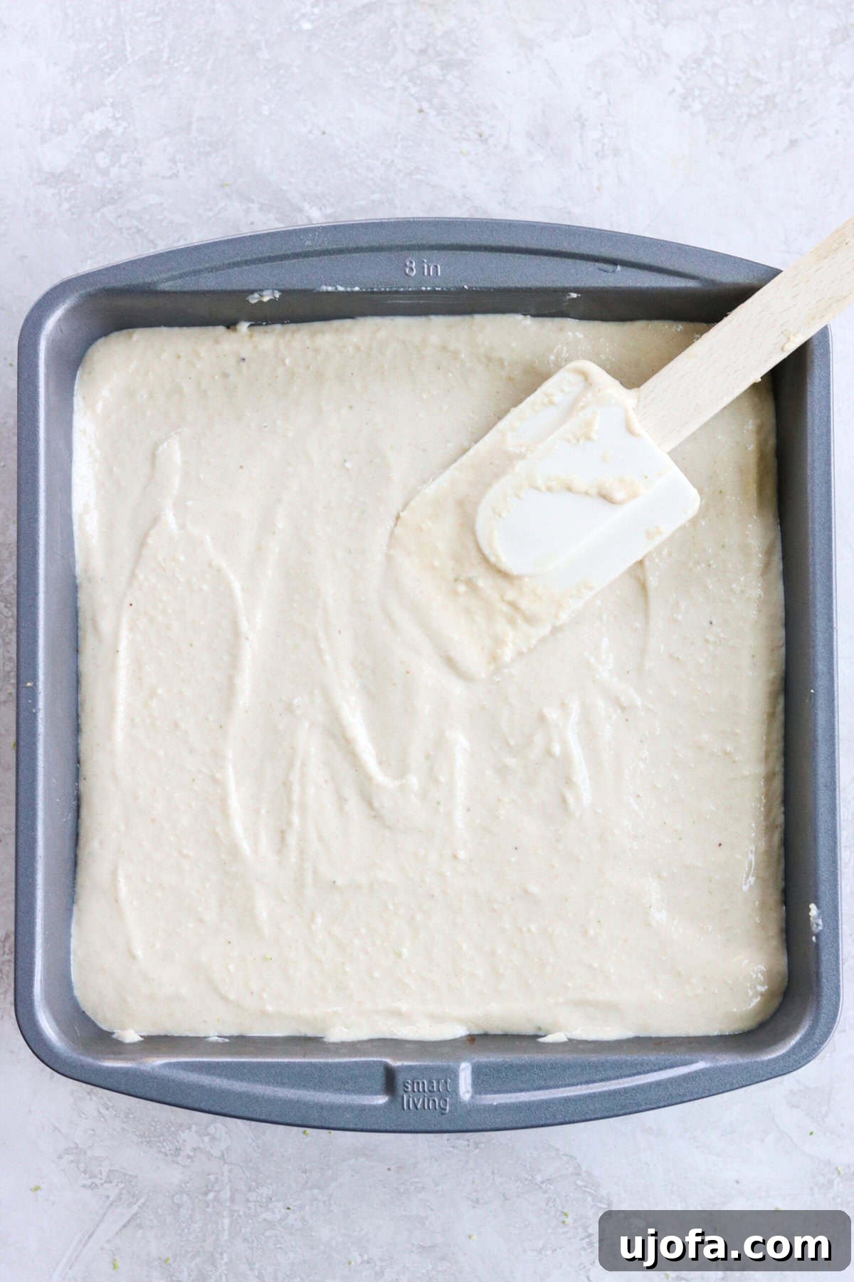 cashew key lime pie bar filling being spread out on the crust with a spatula