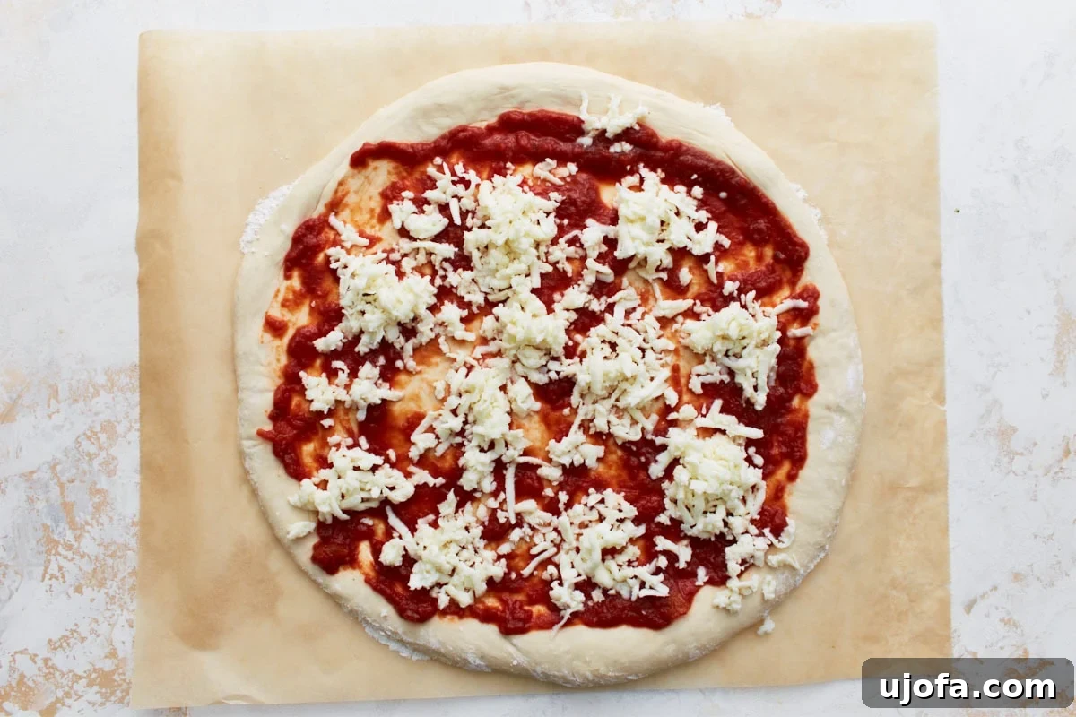 Plant-Based Pizza Perfection 10 The pizza dough topped with tomato sauce and scattered shredded vegan cheese before baking.