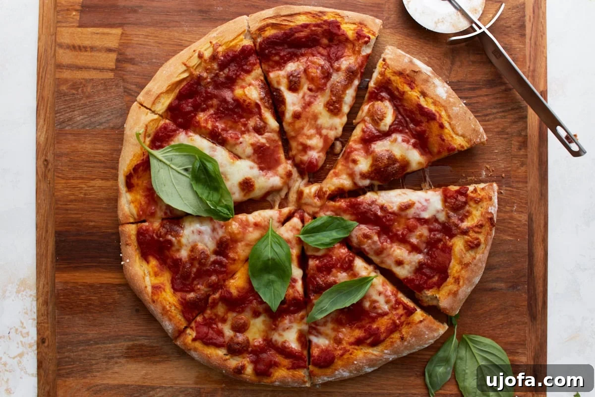 Plant-Based Pizza Perfection 12 The baked vegan pizza cut into slices and topped with fresh basil, a pizza cutter nearby on a wooden board.