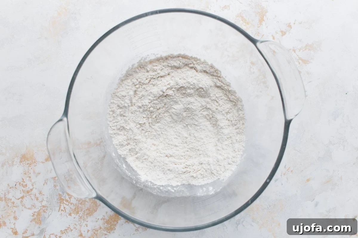Plant-Based Pizza Perfection 5 A glass mixing bowl filled with gluten-free flour, yeast, sugar, and salt before adding wet ingredients.