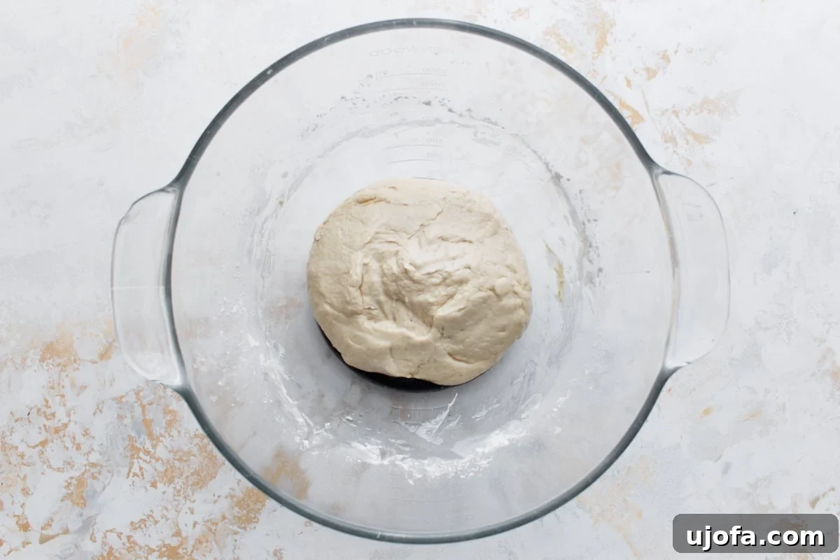 Plant-Based Pizza Perfection 7 A smooth ball of pizza dough resting in a glass bowl after kneading.