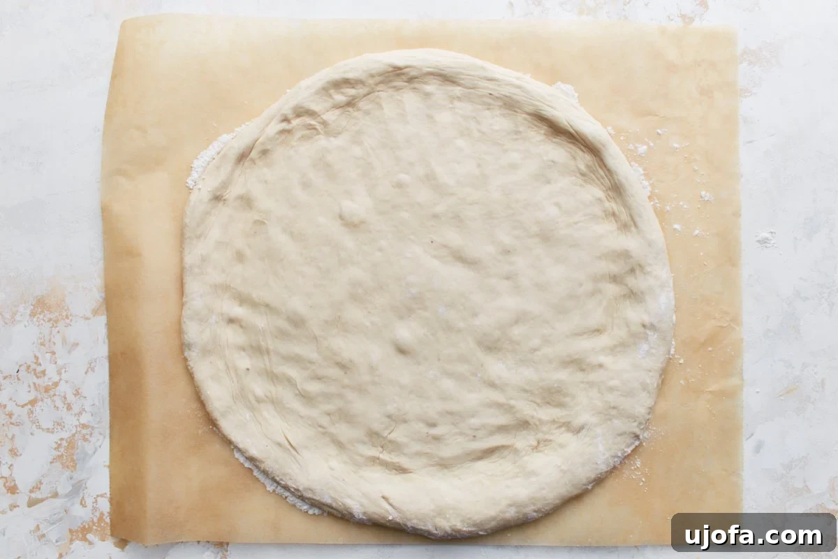 Plant-Based Pizza Perfection 9 The pizza dough flattened into a 12-inch circle on parchment paper, ready for sauce and toppings.