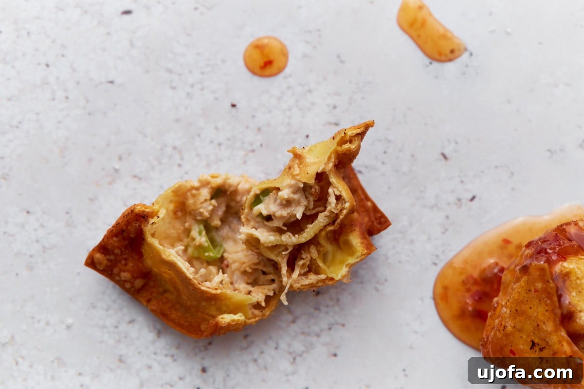 A cooked gluten-free crab rangoon with a bite taken out of it, revealing the creamy filling inside.