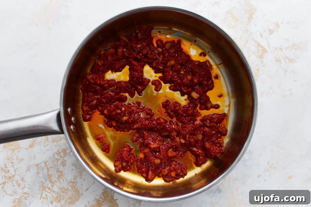 Tomato paste added to the skillet with onions and garlic, starting to cook down.