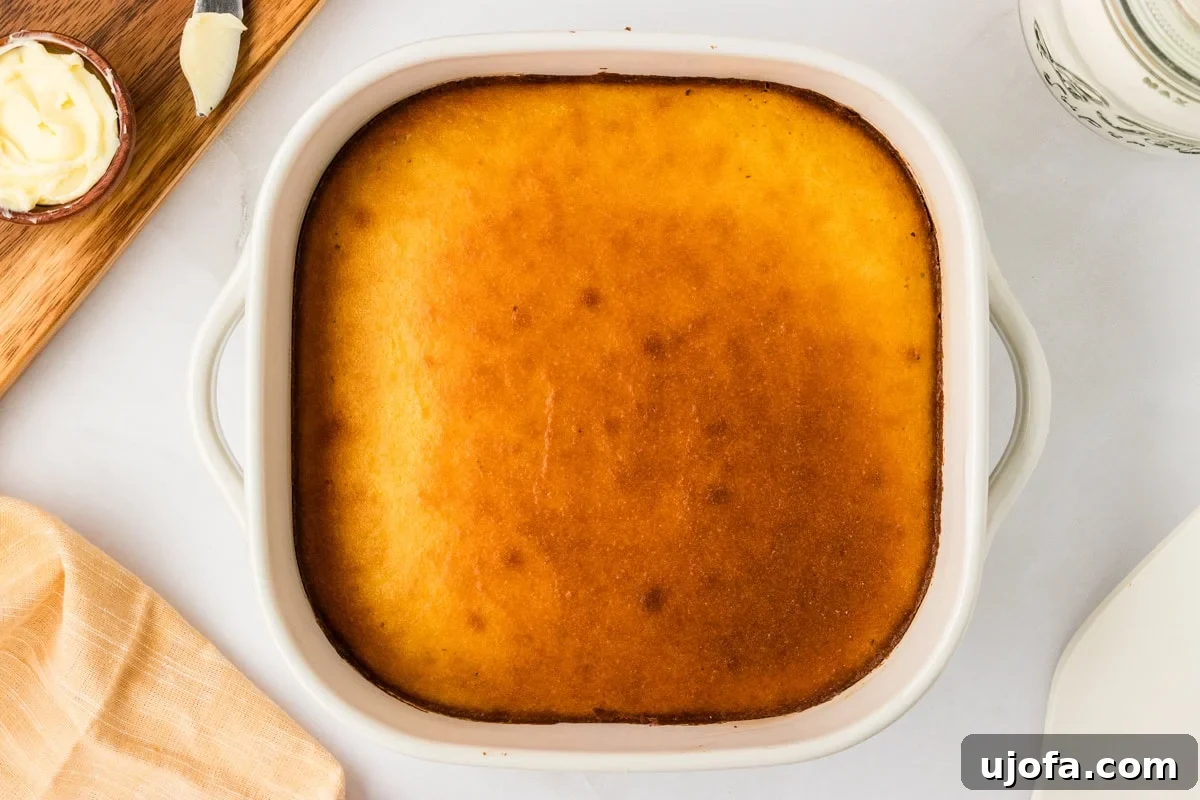 Guilt-Free Golden Cornbread 8 Freshly baked keto cornbread in a white square baking dish, golden brown on top and appearing slightly risen, straight from the oven.