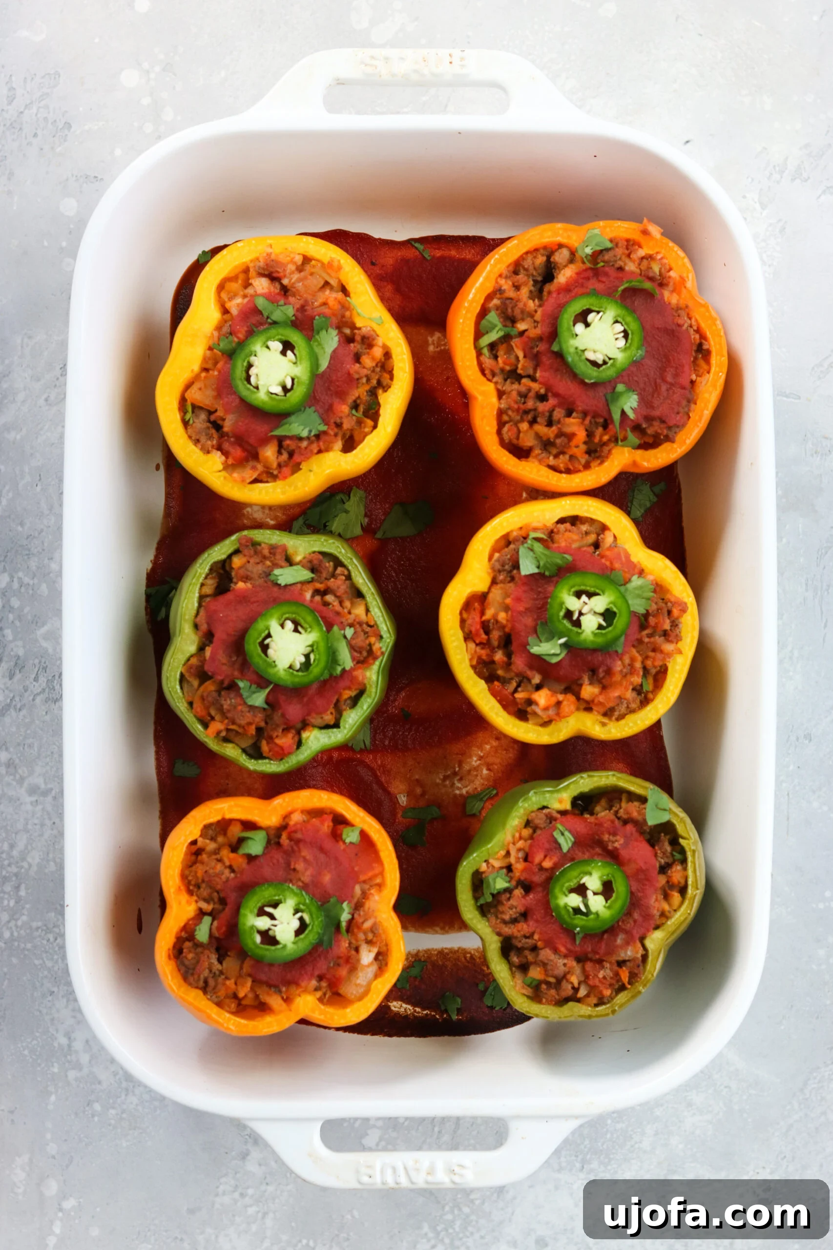 A close-up of a partially prepared Whole30 Taco Stuffed Pepper, showing the rich ground beef and cauliflower rice filling before baking.
