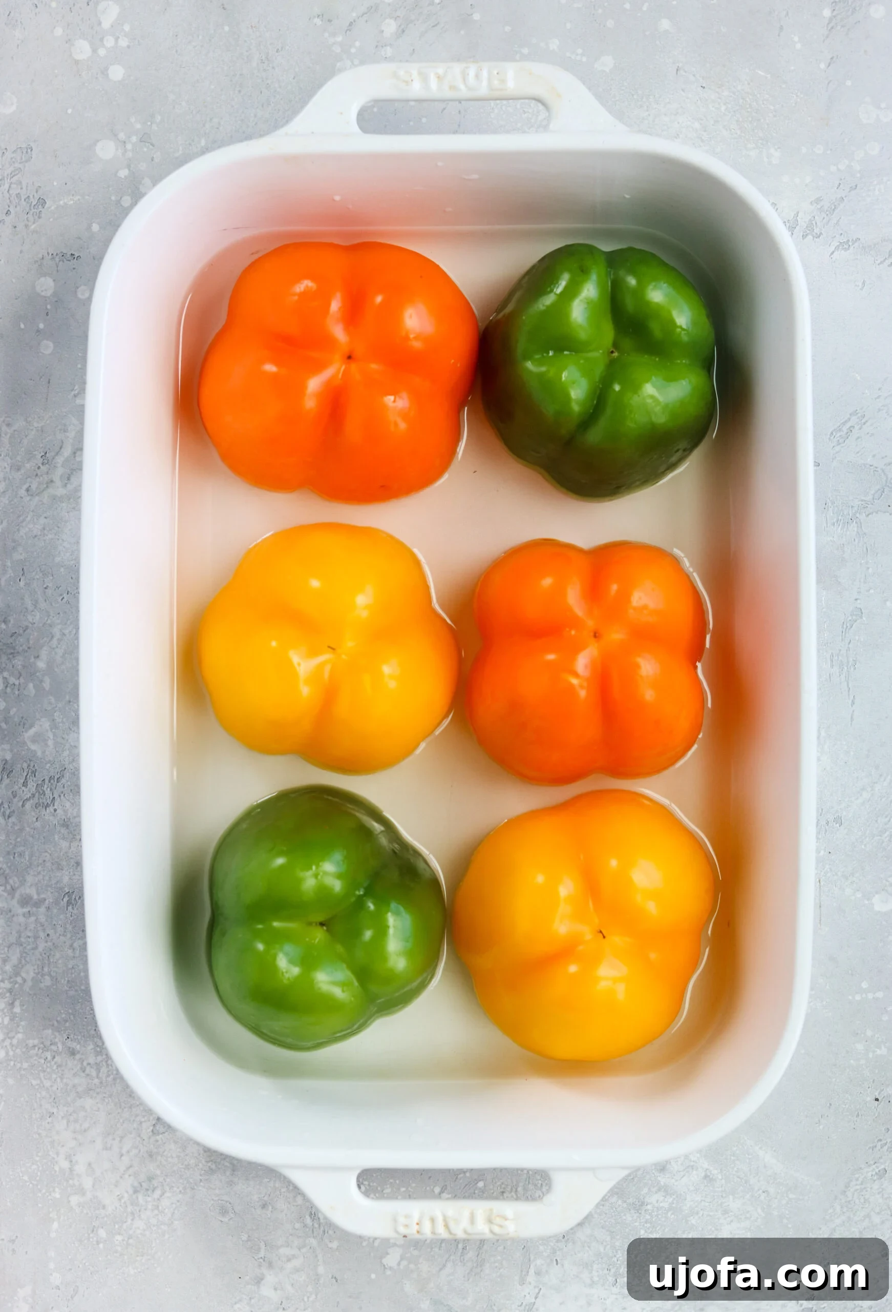 Top-down view of six colorful bell peppers, hollowed out and ready to be stuffed with a healthy, Mexican-inspired filling.