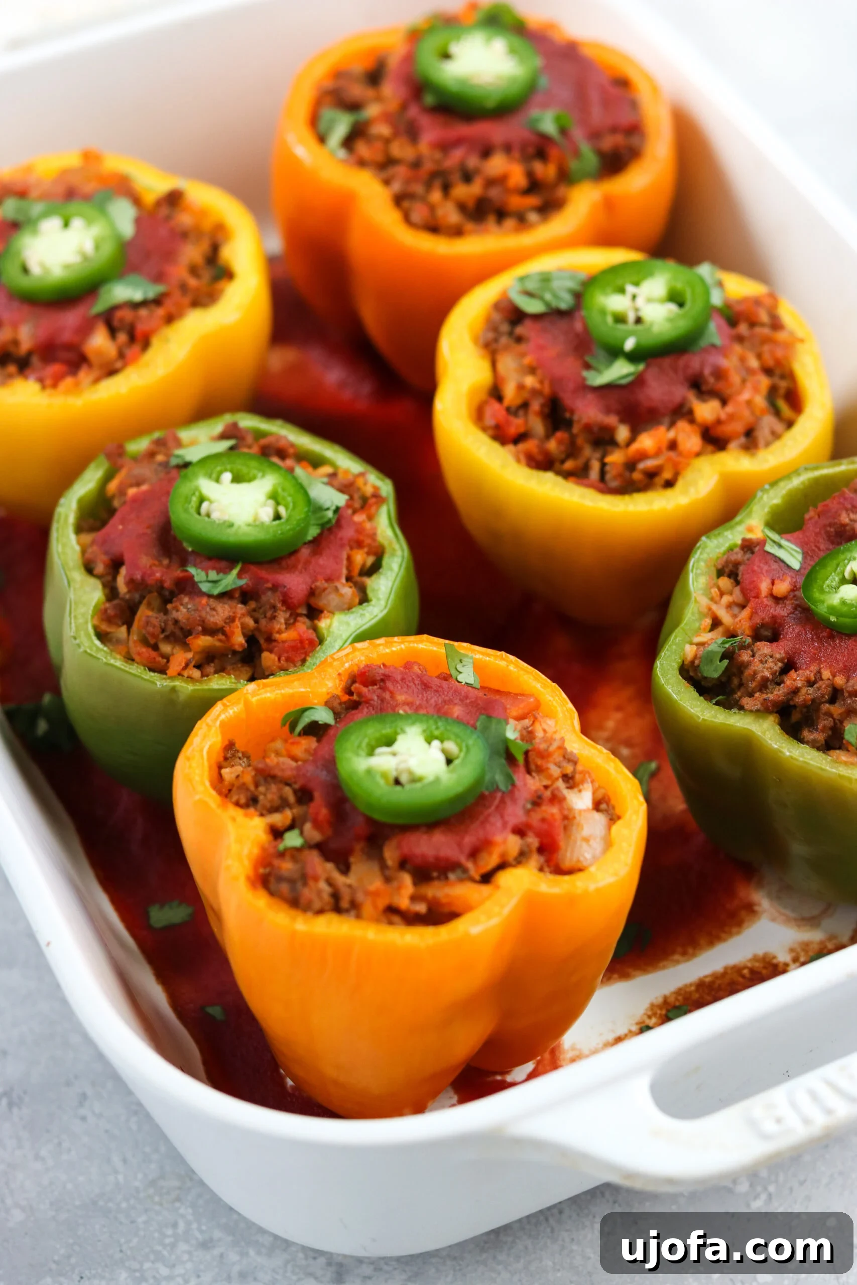 A vibrant platter of Whole30 Taco Stuffed Peppers, topped with fresh cilantro and dairy-free sour cream, ready to be served.