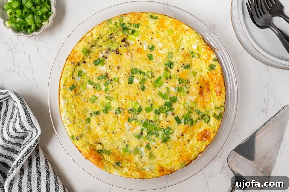 Fluffy Zucchini Egg Bake 10 An beautifully baked crustless zucchini quiche, captured from an overhead perspective, with a golden-brown top and visible fresh green onions, presenting a tempting view ready for serving.