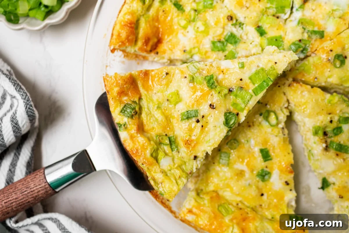 Fluffy Zucchini Egg Bake 11 A delectable slice of crustless zucchini quiche being carefully lifted from the pie dish with a gleaming metal pie server, showcasing its firm yet fluffy texture.