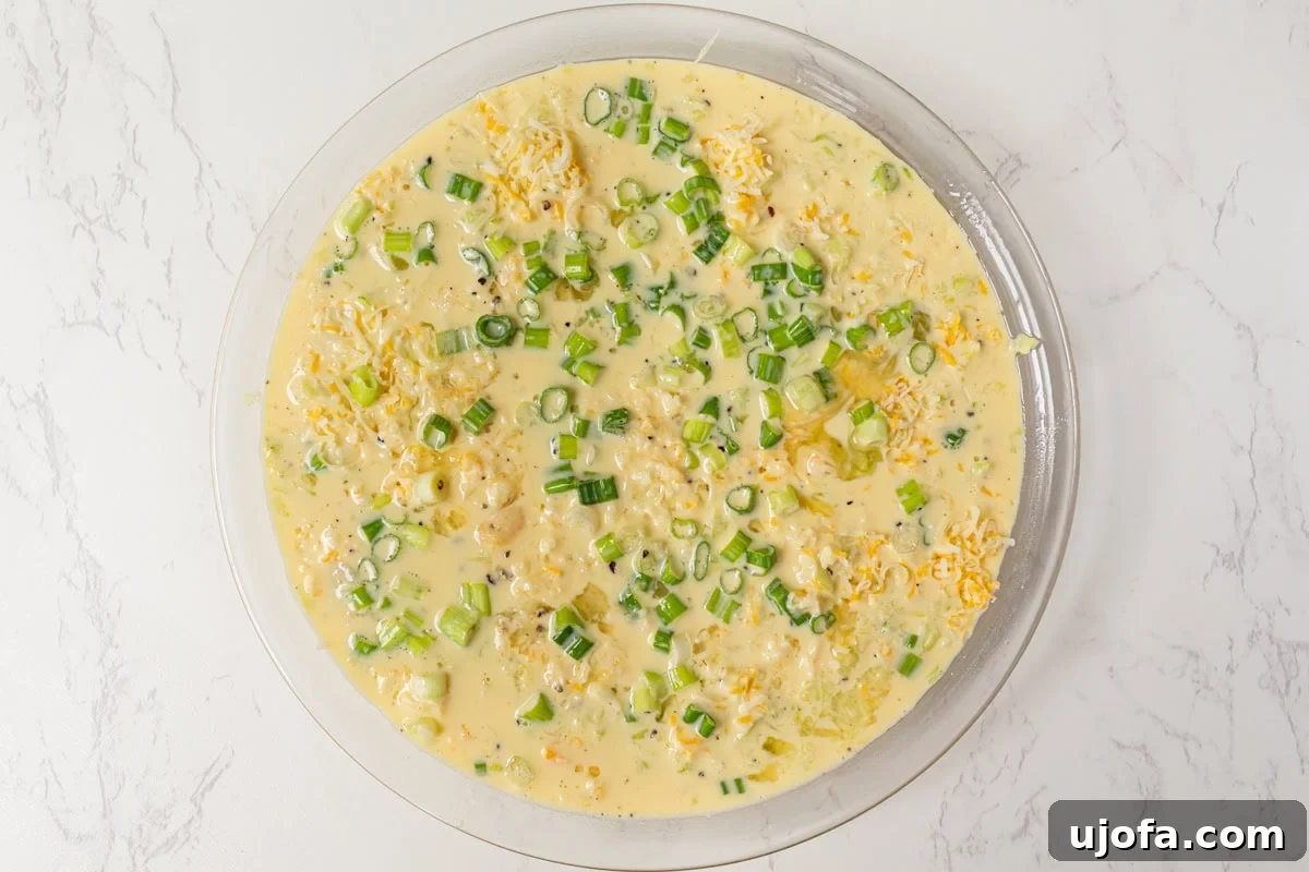Fluffy Zucchini Egg Bake 9 An unbaked crustless zucchini quiche, beautifully arranged in a pie dish, with the vibrant green onions visibly integrated into the egg and cheese mixture, poised for baking.