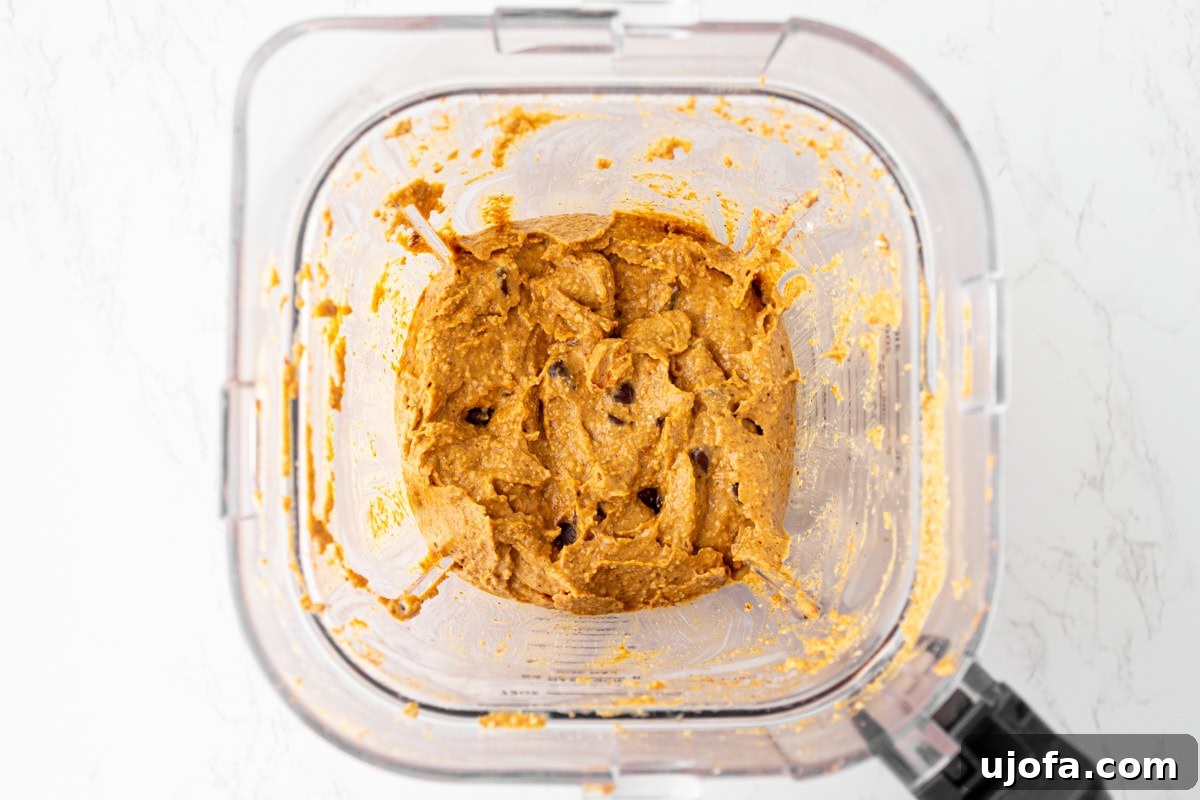 Spiced Pumpkin Cloud Muffins 7 Pumpkin muffin batter fully blended with chocolate chips stirred in, thick and creamy in the blender bowl, showcasing a rich consistency.