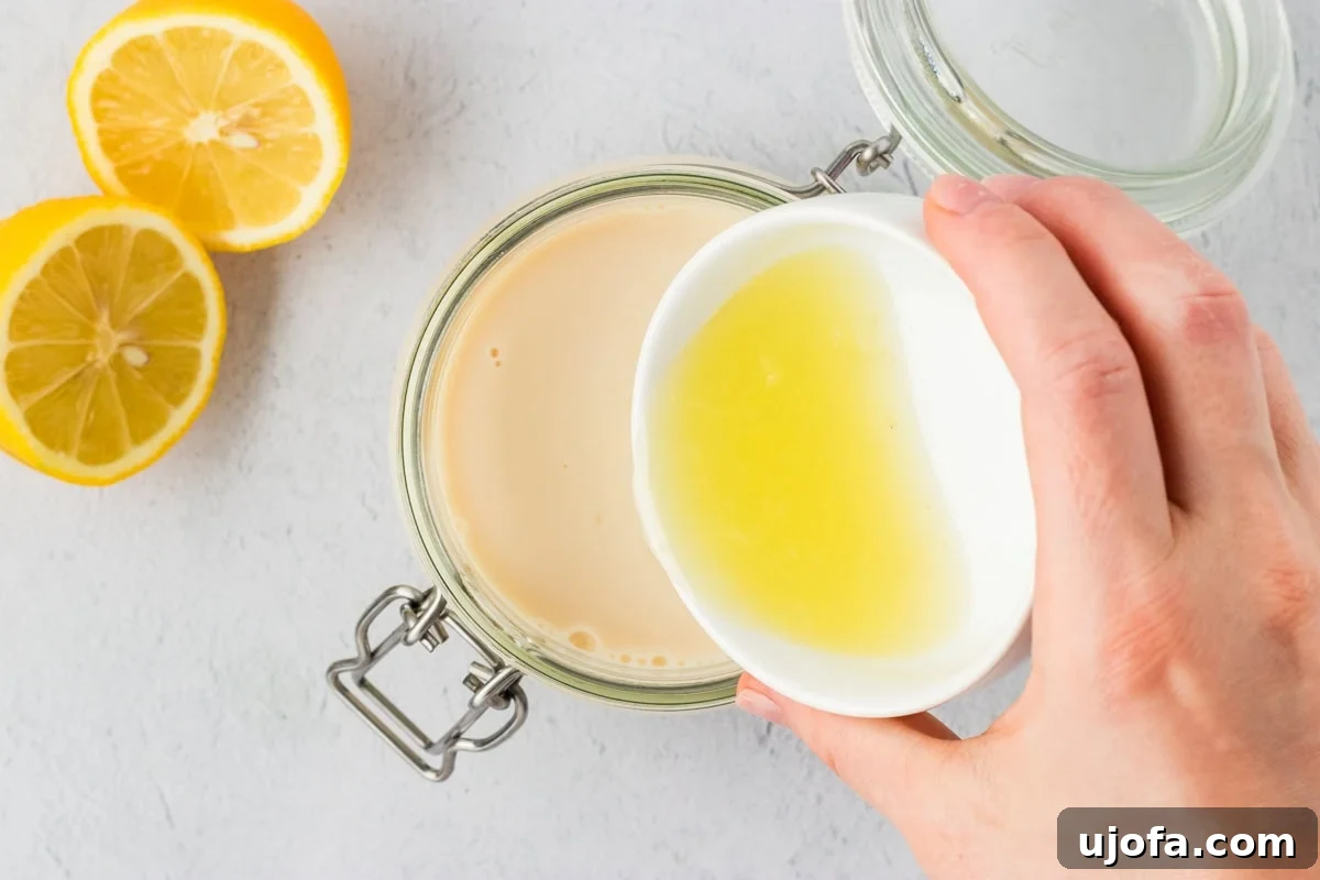 Lemon juice being poured from a small white bowl into a jar of soy milk to make vegan buttermilk, with fresh lemons nearby.