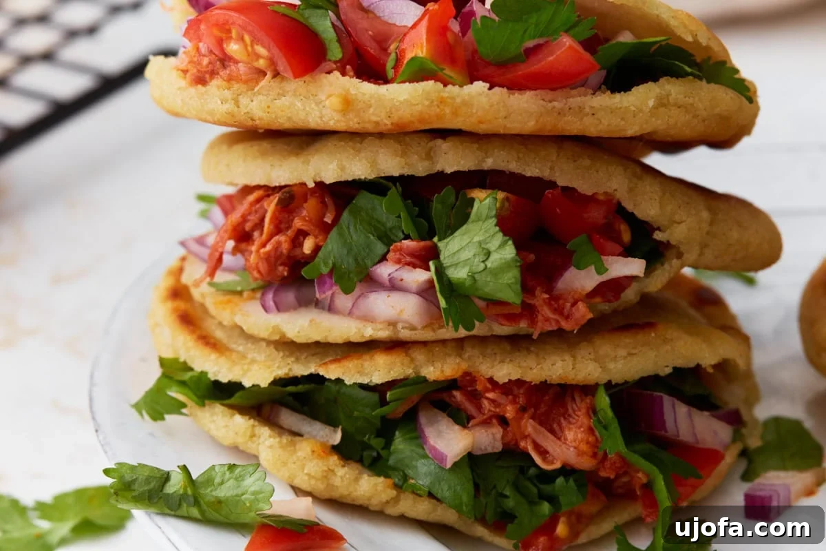 Authentic Mexican Gorditas 11 A vibrant close-up of a stack of gluten-free gorditas, bursting with shredded chicken, fresh tomatoes, finely sliced red onion, and aromatic cilantro, ready to be enjoyed.