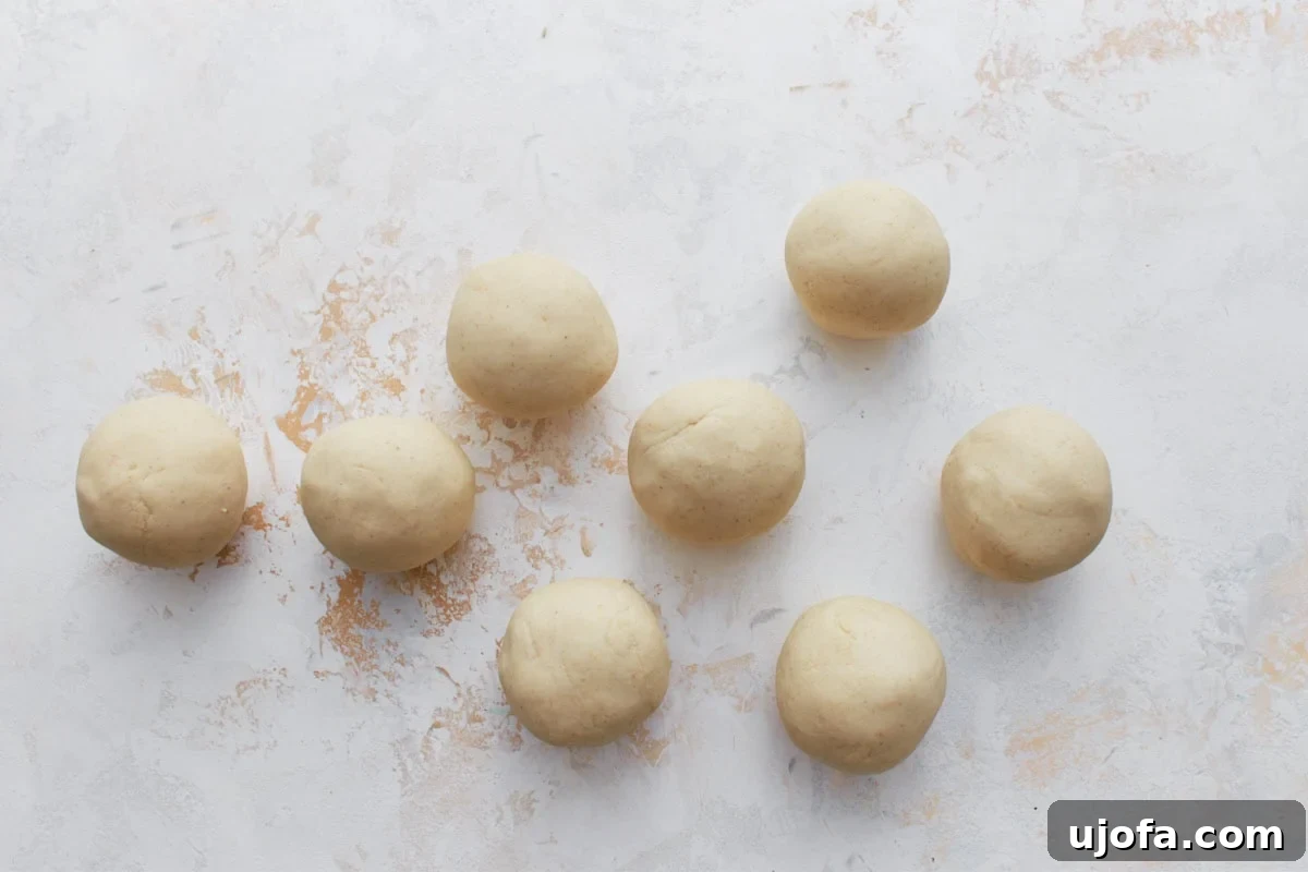 Authentic Mexican Gorditas 7 Eight evenly shaped, perfectly round balls of masa dough arranged symmetrically on a white surface, prepared for the next step of flattening.